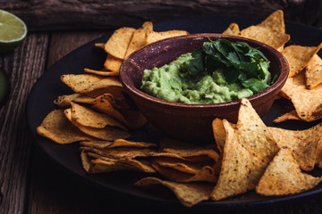 Mexican traditional food, guacamole sauce, ingredients  avocado, cilantro, lime and tortilla corn chips
