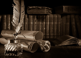 Quill pen and rolled up papyrus sheets with old books, sepia effect