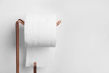 Toilet paper holder with roll near light wall. Space for text