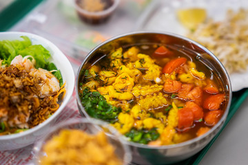Asian food, spicy soup with seafood and vegetables close-up in a bowl, top view