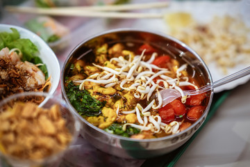Asian spicy soup with vegetables, seafood and germinated soybean sprouts in a bowl close-up, top view. Gastronomic gourmet food on market counter, real scene