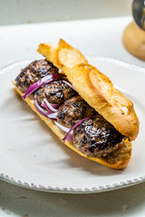 Turkish Kofte Ekmek / Meatball Sandwich with Red Onions. Traditional Fast Food from Turkey.