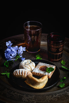 Traditional tea with mint and assorted homedade Arab sweets on dark background. Ramadan. Islamic. Halal