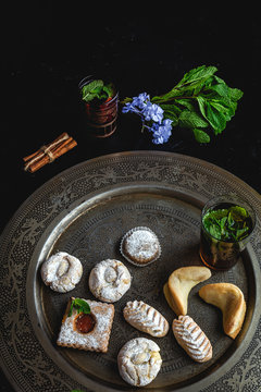 Traditional tea with mint and assorted homedade Arab sweets on dark background. Ramadan. Islamic. Halal