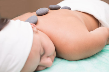 Portrait of a young woman blissfully enjoying spa therapy. close-up. Massage stones