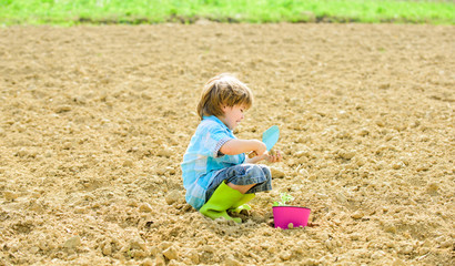 small kid planting a flower. earth day. new life. summer farm. happy child gardener. botanic worker. Spring season. ecology life. eco farm. human and nature. natural soil. new technology in farming