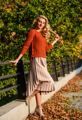 Cute smiling woman. sunny day with leaves. fall fashion season. girl in corrugated skirt and sweater. Pleated trend. female beauty. Femininity and tenderness. autumn woman outdoor. girl in park