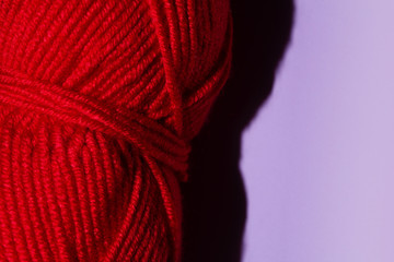 Red skein of thread for knitting on a purple background, copy space. macro