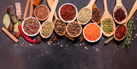 A set of spices and herbs. Indian cuisine. Pepper, salt, paprika, basil and other on a dark background