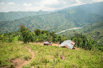 Uganda - November 26, 2016: From above magnificent scenery of countryside with small cultivated fields and solitary village among hills with green lush grass and dense forests