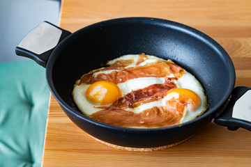 Fried Eggs with Prosciutto in Pan for Breakfast. Ready to Eat.