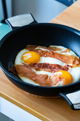 Fried Eggs with Prosciutto in Pan for Breakfast. Ready to Eat.