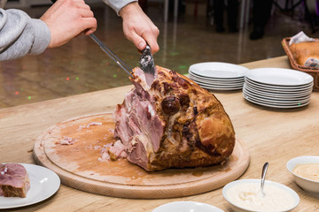 Close-up of roasted meat. Sliced pork leg on a wooden tray.