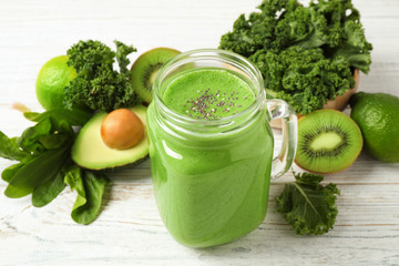 Tasty fresh kale smoothie on white wooden table