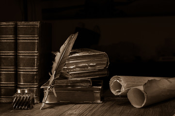 Quill pen and rolled up papyrus sheets with old books, sepia effect