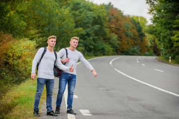 Obraz premium męskie plecaki idące razem drogą. bliźniaki idące drogą. Przygoda i odkrycie. Mężczyzna z plecakiem autostopem na drodze. Letnie wakacje. Zatrzymanie podróży turystów turystycznych. Niedrogie podróżnicy