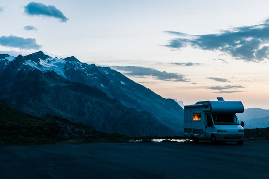 White camper moving on road along lake with crystal water in twilight in Switzerland 