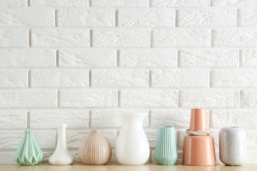 Different ceramic vases on white brick wall background