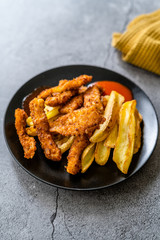 Fish and Chips made with Breaded and Fried Seabass in Black Plate.