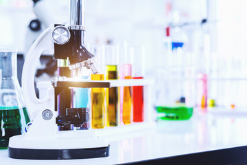 Microscope and test tubes with lab glassware in laboratory background, research and Scientific concept