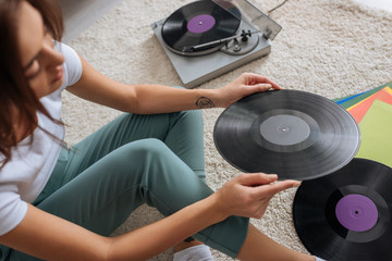 selective focus of tattooed girl holding vinyl record at home