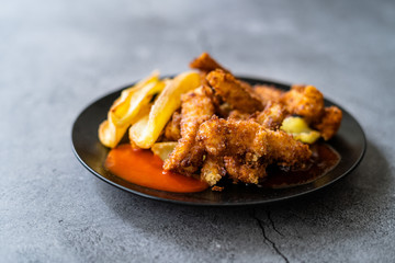 Fish and Chips made with Breaded and Fried Seabass in Black Plate.