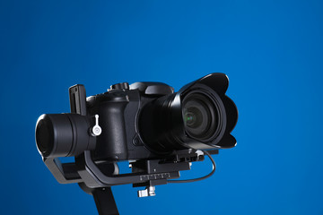 Modern professional video camera on blue background