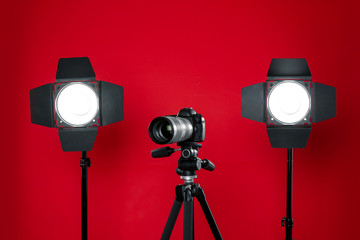 Professional video camera and lighting equipment on red background