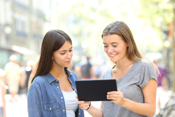 Friends watching tablet content standing in the street