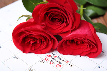 Bouquet of red roses and paper february calendar with text Happy Valentine's Day
