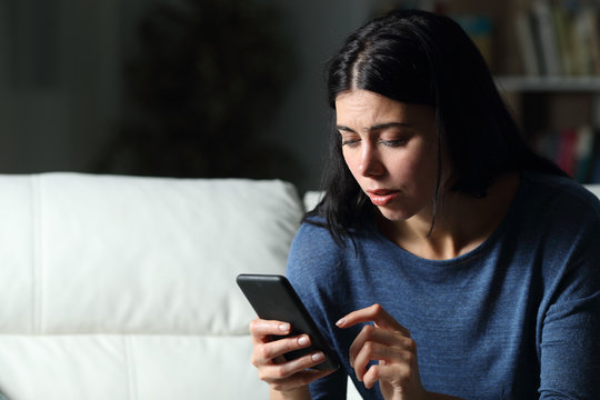 Worried woman checking cell phone text in the night