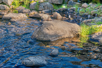 Fototapeta premium Small fontains in a park next to stones