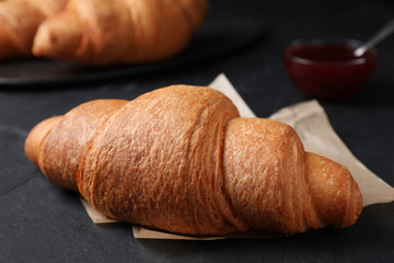 Tasty fresh croissant on black table, closeup