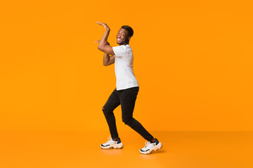 Fototapeta na wymiar Black Guy Dancing In Egypt Style Having Fun, Orange Background