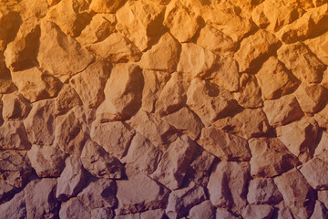 Beautiful rough marble stone wall background illuminated by golden hour sunlight during a hot summer afternoon