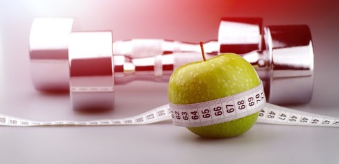 Dumbbell with green apple and tape measure on desk © BillionPhotos.com