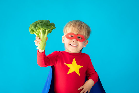 Superhero child holding broccoli