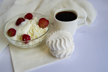 Coffee, cottage cheese with strawberries, marshmallows on a white background. Good morning.Simple meal.