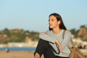 Fototapeta premium Confident woman looking away sitting on the beach