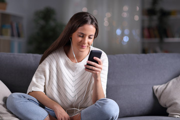 Obraz premium Girl with earphones listening to music on phone in the night