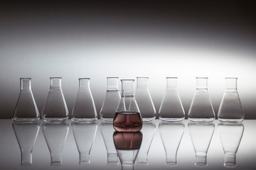 Scientific laboratory glass erlenmeyer flask filled with purple liquid with glassware equipment on...