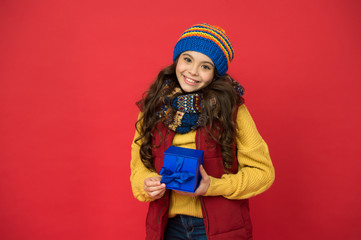Winter holidays. Happy kid in winter outfit red background. Pick some winter gifts for yourself. Wish list. Feeling grateful. Holidays season. Happy childhood. Christmas gifts and souvenirs