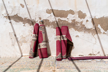 Four rolled up carpets leaning against wall at sunlight, Fez, Morocco