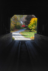 old New England covered bridge leading to a caountry road in fall season