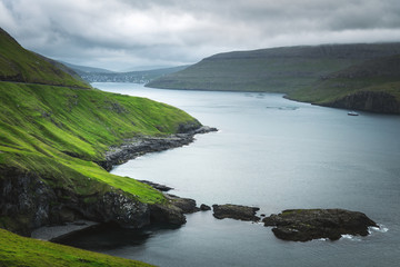 Obraz premium Dramatic view of green hills of Vagar island and Sorvagur town on background. Faroe islands, Denmark. Landscape photography
