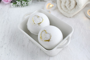 Obraz na płótnie Canvas Close up bath bombs with heart in ceramic bowl, towel on white background. Romantic spa luxurios composition. Love concept for Valentines day, Mothers day or wedding