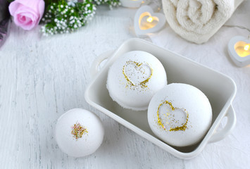 Fototapeta na wymiar Bath aroma bombs set with heart, towel on white background. Romantic spa luxurios composition. Love concept for Valentines day, Mothers day or wedding