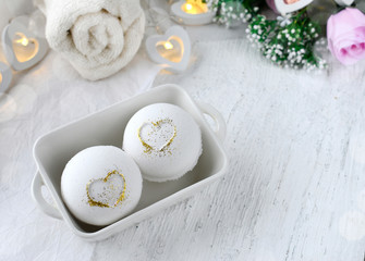 Fototapeta na wymiar Couple of bath bombs with heart in ceramic bowl, towel on white background. Romantic spa beauty composition. Concept for Valentines day, Mothers day or wedding. Copyspace.