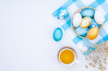 Top view of easter eggs in a plate on a rustic kitchen table with a cup of tea. Checkered tablecloth. Copy space