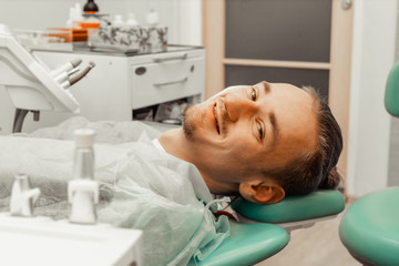A young and satisfied male patient in the dentist's chair. Smiling at the camera. Health and medicine.
